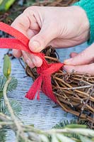 Creating a hanging hoop for wreath out of red hessian ribbon