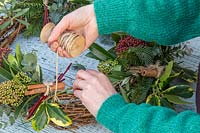Securing stem of Ilex - holly - onto wreath with string