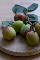 Plums on a rustic wooden platter. 