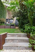 Steps leading up to lawn, terrace and outdoor kitchen with pizza oven.