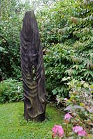 Carved abstract wooden sculpture on lawn.