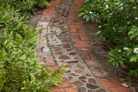 Brick and stone path winding between plant beds