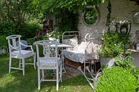 Relaxing area in shade, an old decorative bed, antique chairs and planted pots