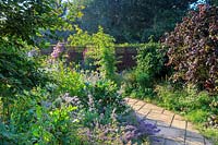 Looking down the curving pathway in the the tiny cottage garden at the front of the house. Tyger Barn, Norfolk, UK.
