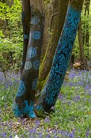 blue patterns painted on tree in bluebell wood