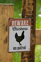 Humorous chicken sign on fence. 