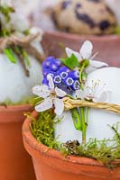 Eggs in terracotta pots decorated with flowers and feathers