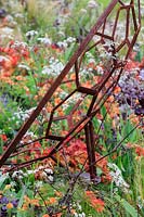 Detail of sculpture depicting a telescope surrounded by mixed planting. The Red Shift Garden, designed by Julie Bellingham. RHS Malvern Spring Festival, 2019. 
