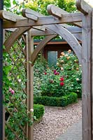 View through wooden arch to the Buxus-edged borders in the traditional rose garden, in garden of designer Karen Tatlow.
