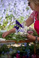 Florist making hand-tie of blue and white delphiniums at flower farm. 