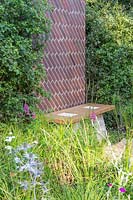 Brick screen between hedging, by a bench of Scottish oak with staddle stones in 
'South Oxfordshire Landscape Garden'