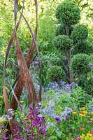 Simon Probyn sculpture amongst flowers with cloud-pruned tree in the 'Brilliance in Bloom' garden 
