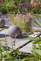 Paving area with paving, chippings, spheres and ornamental grasses in the 
'Secured by Design' garden