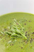 Bowl of Pea soup with green pea shoots and pepper
