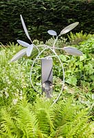 The Olive - artwork in aluminium and cement - set amongst green foliage
