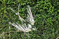 Birds and Bees - artwork made from steel cutlery - displayed against hedge
