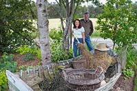 Couple standing by a garden feature comprising an old rowing boat with sculptured 
fly-fisherman 