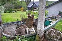 Garden feature of an old rowing boat, fly-fisherman made from moss and 
chicken wire, wicker baskets, net and fishing rod