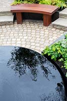 'The Thrive Reflective Mind' garden, infinity pool, raised bed on paving near wooden bench
  