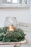 Natural Hydrangea 'Aspera' and Fir Christmas wreath with glass lantern with lit candle as a table decoration