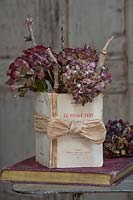 Red dried Hydrangea flower heads and twigs in vintage book vase 