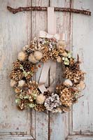 Dried wreath hung on vintage French doors. Wreath made from: Hydrangea
flowers, seedheads, pine cones and pheasant feathers.
