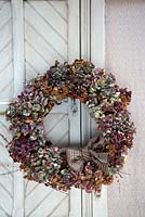 Multicoloured dried Hydrangea wreath on French cupboard door