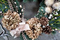Close up of wreath showing dried Hydrangea flowers ,pine cones, mistletoe, 
snowberries, pheasant feathers and seed heads