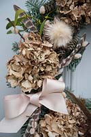 Close up of natural foraged wreath showing ribbon bow and dried Hydrangea flowers

