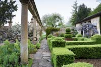 The Casita with wisteria, clipped box parterre and colonnade on the Great Terrace at Iford Manor, Bradford-on-Avon, Wiltshire, UK. 