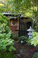 View past stone lantern to traditionally styled bench in Japanese themed garden.
