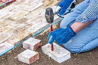 Man using chisel and hammer to cut brick in half.