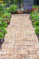 Finished basket-weave brick path, edged with vegetables and flowers. 