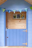 Blue door of a children's playhouse in garden. 