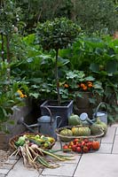 Harvested produce in baskets beside watering cans in potager