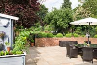 Patio area with dining furniture and umbrella - view to retaining wall and lawn