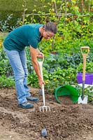 Woman forking in grit in preparation for herb garden