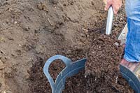 Adding well rotted manure using a fork