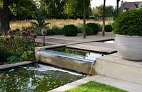 Modern water feature, waterfall and pool in contemporary garden.
