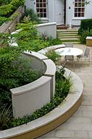 Greenery growing between curved wall and benching in modern urban garden. 