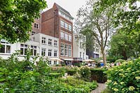 The communal garden at De Bary, Amsterdam, The Netherlands, designed by Cilia Prenen. View to the apartments facing the garden, from one end, with visitors enjoying the garden. 
