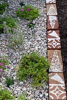 A row of stencilled bricks separate the gravel garden and flowerbed. 