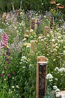 A line of bug hotels surrounded by flowering perennials in BBC Springwatch garden, RHS Feature Garden, RHS Hampton Court Palace Garden Festival, 2019.
