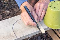 Woman using a wooden label to mark the shape ready for cutting