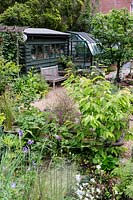View of garden with pergola, garden chair, shed and greenhouse