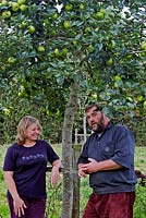 Anne Swithinbank and Kevin Croucher having a chat by apple tree - Proprietor of Thornhayes Nursery, Devon, UK.

