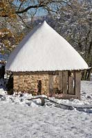 Summerhouse in the snow at Burrow Farm Garden, Dalwood, Devon, UK. 