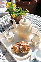 Tea pot, cups and hot cross buns on garden table 