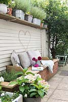 Raised bed with built in seating and shelf for display of container planting