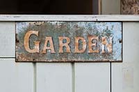 Old vintage painted garden sign on a garden gate. 